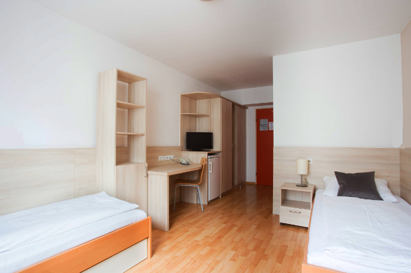 اتاق دو نفره با تخت های جدا و ملحفه های سفید در خوابگله اتریش